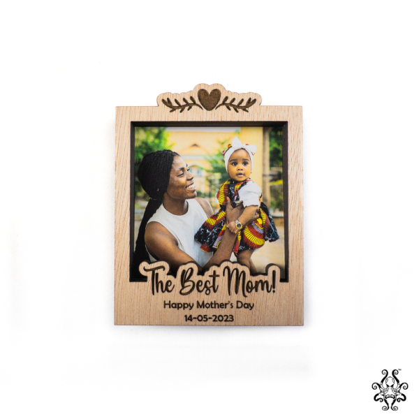 A wooden magnetic polaroid frame with a personalised Mother's Day message, featuring a photo of a mother holding her baby, engraved with "The Best Mom!"